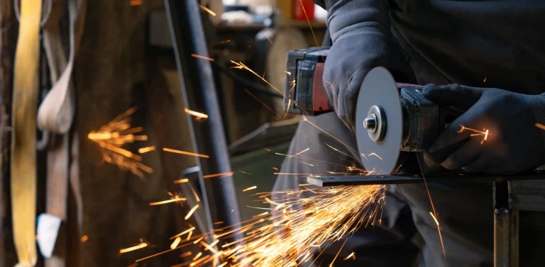 Persona con amoladora en las manos que corta metal